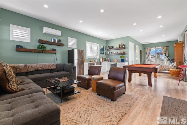 living room featuring pool table, light wood-type flooring, and an AC wall unit