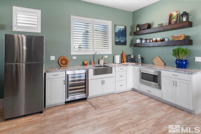 kitchen with stainless steel appliances, beverage cooler, white cabinets, and sink