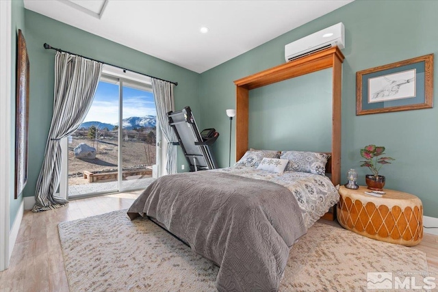 bedroom featuring access to exterior, light hardwood / wood-style floors, a wall mounted air conditioner, and a mountain view