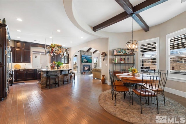 dining area with sink, dark hardwood / wood-style flooring, an inviting chandelier, and beam ceiling