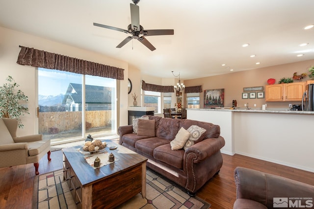 living room featuring ceiling fan with notable chandelier, a fireplace, and hardwood / wood-style flooring