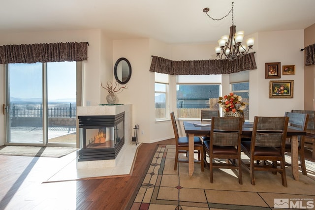 dining space with a multi sided fireplace, an inviting chandelier, and hardwood / wood-style floors