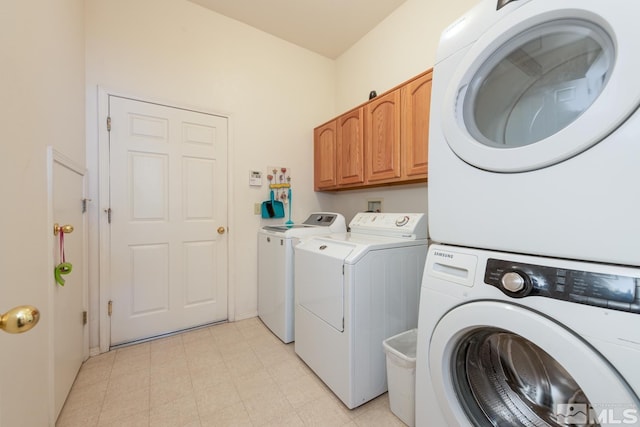 clothes washing area with washer and clothes dryer and cabinets