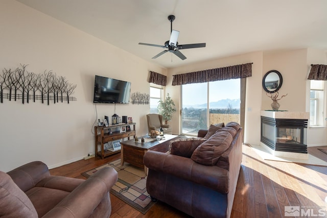 living room featuring a multi sided fireplace, ceiling fan, and hardwood / wood-style flooring