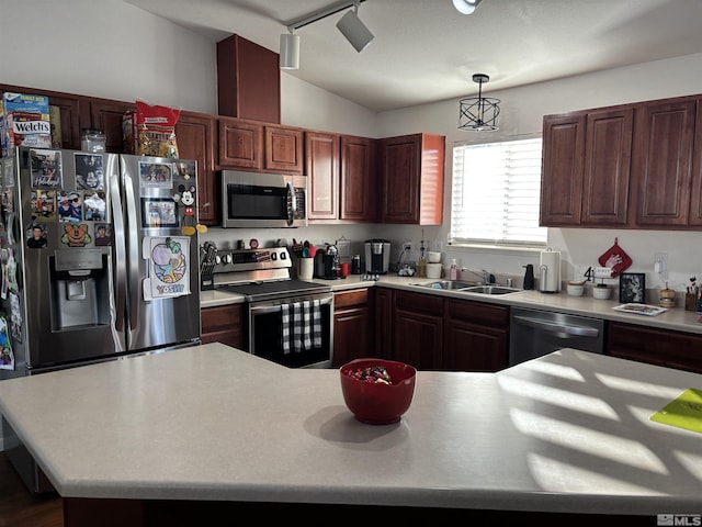 kitchen with vaulted ceiling, stainless steel appliances, track lighting, pendant lighting, and sink