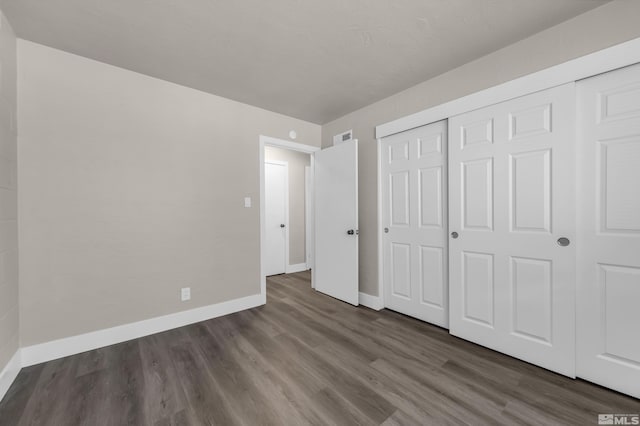 unfurnished bedroom with a closet and dark hardwood / wood-style flooring