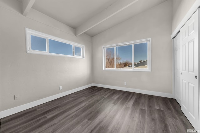 unfurnished bedroom with lofted ceiling with beams, dark wood-type flooring, a closet, and multiple windows