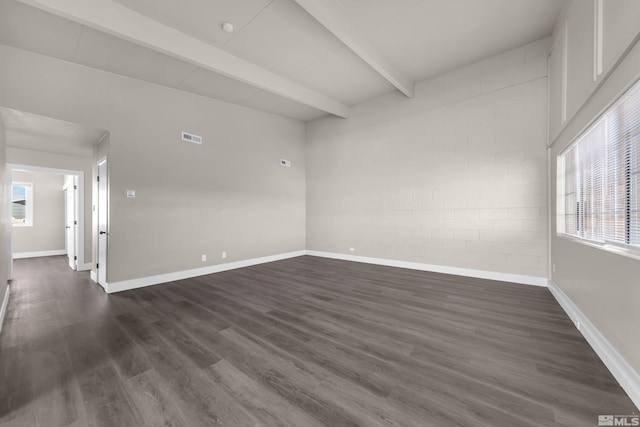 empty room with dark wood-type flooring, plenty of natural light, and beamed ceiling