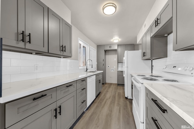 kitchen with tasteful backsplash, sink, white appliances, light hardwood / wood-style flooring, and gray cabinetry