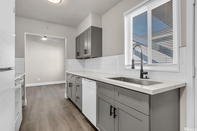 kitchen with gray cabinets, ceiling fan, white appliances, light wood-type flooring, and sink