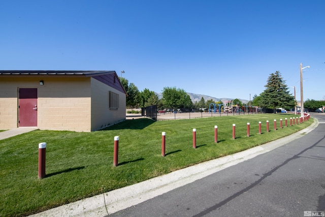 surrounding community with a playground, a mountain view, and a yard