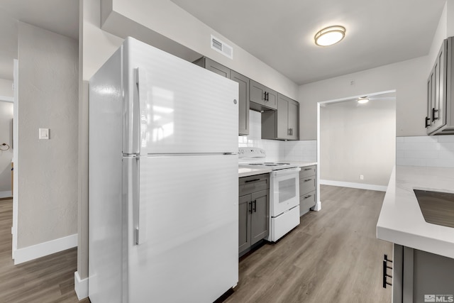 kitchen featuring backsplash, white appliances, gray cabinets, and hardwood / wood-style floors