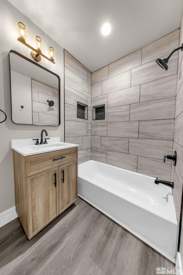 bathroom with tiled shower / bath combo, hardwood / wood-style flooring, and vanity