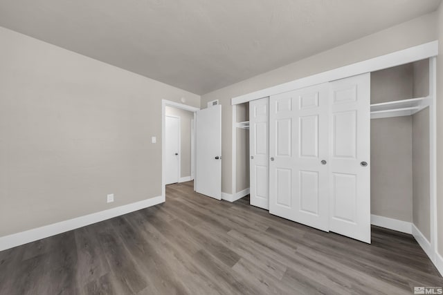 unfurnished bedroom with dark hardwood / wood-style flooring and a closet