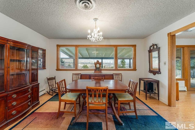 dining room with a baseboard radiator, a notable chandelier, light hardwood / wood-style flooring, and a textured ceiling