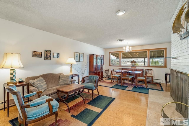 living room featuring a fireplace, a textured ceiling, a notable chandelier, and light hardwood / wood-style flooring