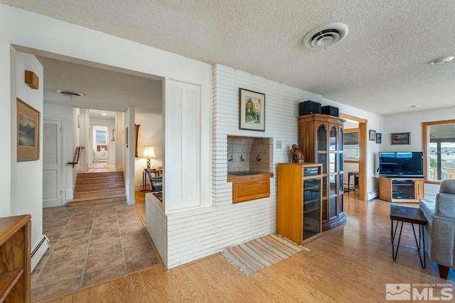 kitchen featuring hardwood / wood-style floors, a textured ceiling, and baseboard heating