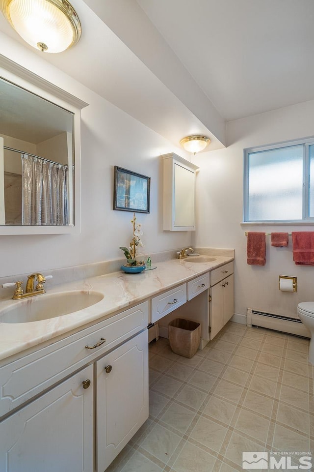 bathroom featuring toilet, vanity, and a baseboard heating unit