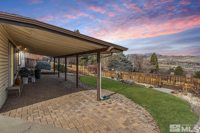 patio terrace at dusk with a yard and a mountain view