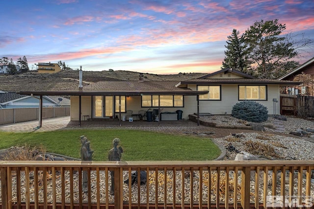 back house at dusk with a yard and a wooden deck