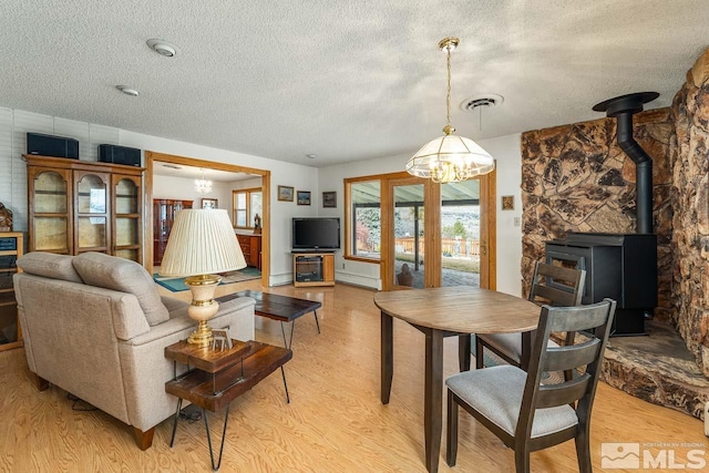 living room featuring a notable chandelier, light hardwood / wood-style floors, and a wood stove