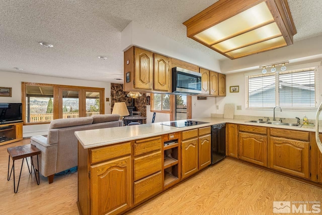 kitchen featuring sink, a textured ceiling, light hardwood / wood-style floors, kitchen peninsula, and black appliances