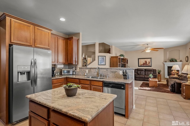 kitchen featuring appliances with stainless steel finishes, light stone countertops, a kitchen island, sink, and light tile patterned flooring