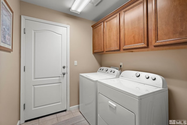 washroom with cabinets, light tile patterned floors, and washer and clothes dryer