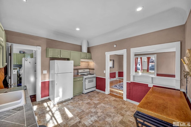 kitchen with sink, green cabinetry, white appliances, and decorative backsplash