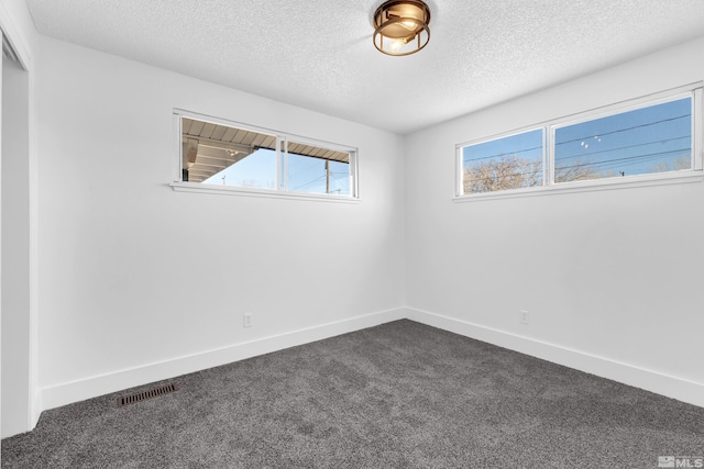 spare room with dark carpet and a textured ceiling