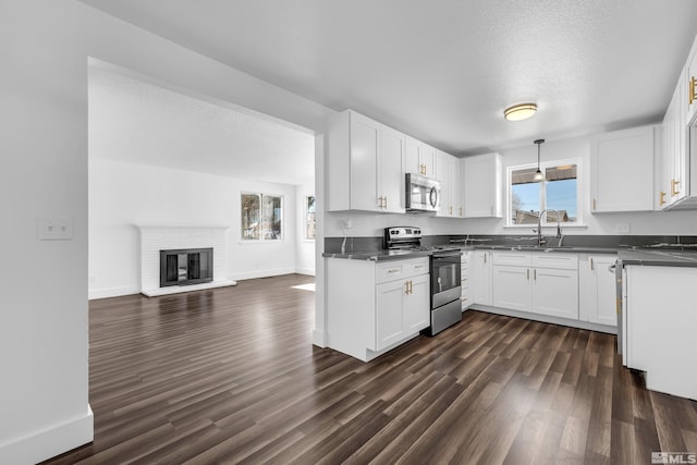 kitchen featuring decorative light fixtures, white cabinets, appliances with stainless steel finishes, and sink