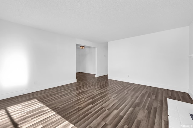 spare room featuring a textured ceiling and dark hardwood / wood-style floors