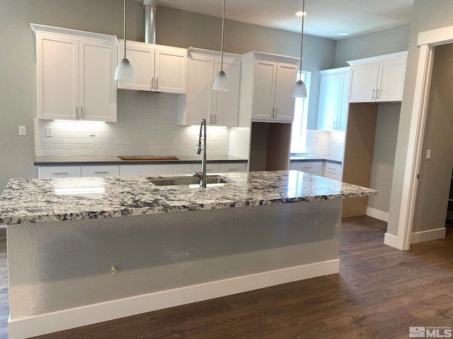 kitchen featuring sink, pendant lighting, white cabinetry, and a center island with sink