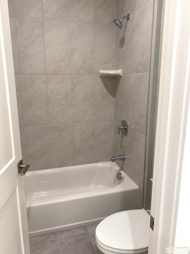 bathroom with tiled shower / bath, tile patterned floors, and toilet