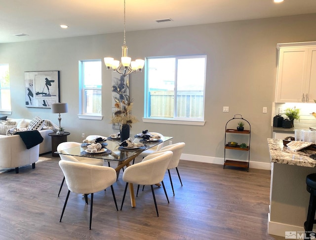 dining room with dark wood-type flooring, a notable chandelier, and a wealth of natural light