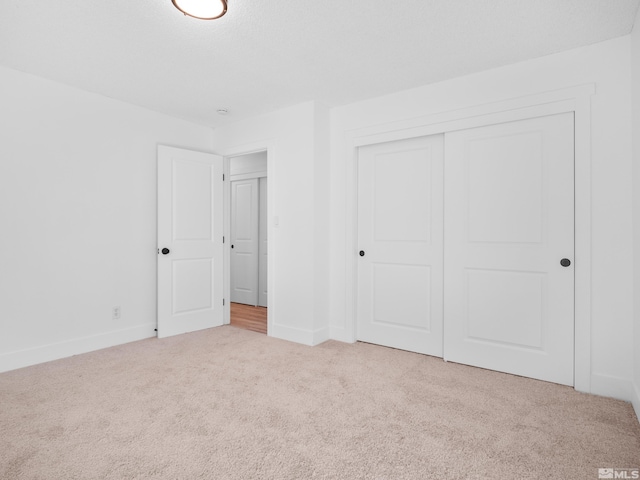 unfurnished bedroom featuring a closet and light colored carpet