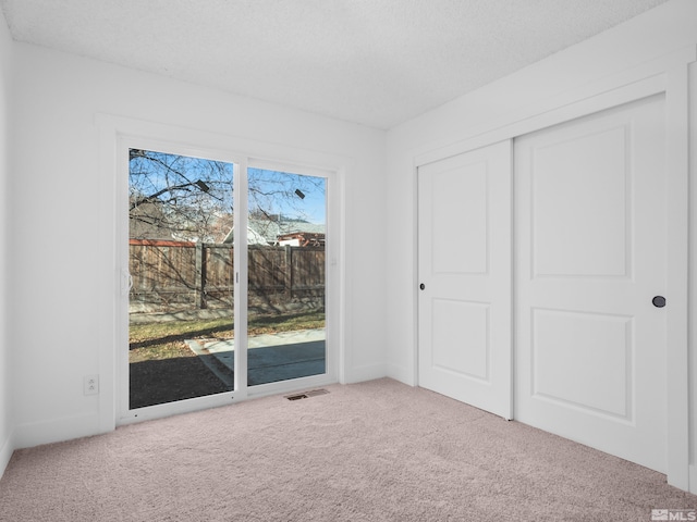 unfurnished bedroom featuring carpet flooring, a closet, and access to outside