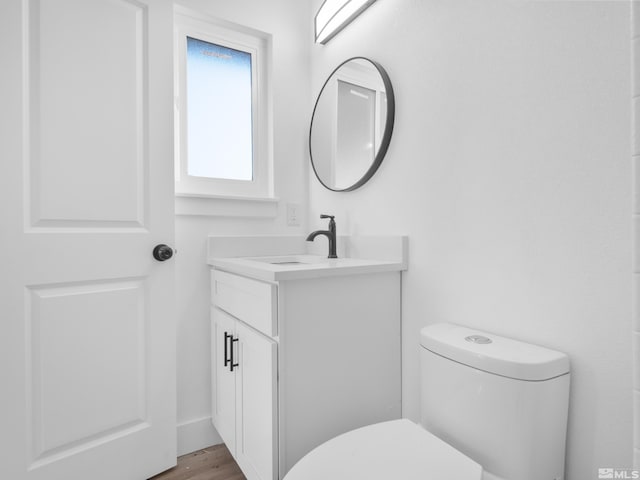 bathroom with toilet, wood-type flooring, and vanity