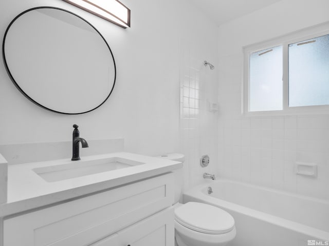 full bathroom with tiled shower / bath, vanity, and toilet