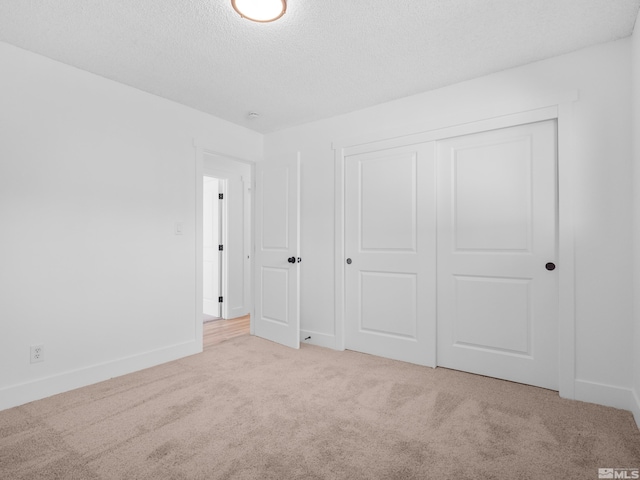 unfurnished bedroom with a textured ceiling, light colored carpet, and a closet