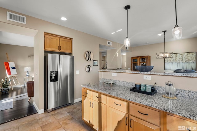 kitchen with a notable chandelier, stainless steel fridge, light stone countertops, and hanging light fixtures