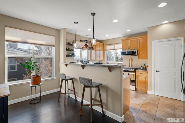 kitchen featuring decorative light fixtures, kitchen peninsula, a breakfast bar area, light stone countertops, and appliances with stainless steel finishes