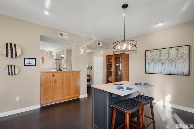 kitchen featuring a breakfast bar area, kitchen peninsula, pendant lighting, dark hardwood / wood-style flooring, and an inviting chandelier