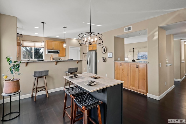 kitchen featuring kitchen peninsula, decorative light fixtures, stainless steel appliances, a notable chandelier, and a breakfast bar