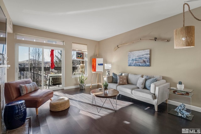 living room with a tile fireplace and dark wood-type flooring