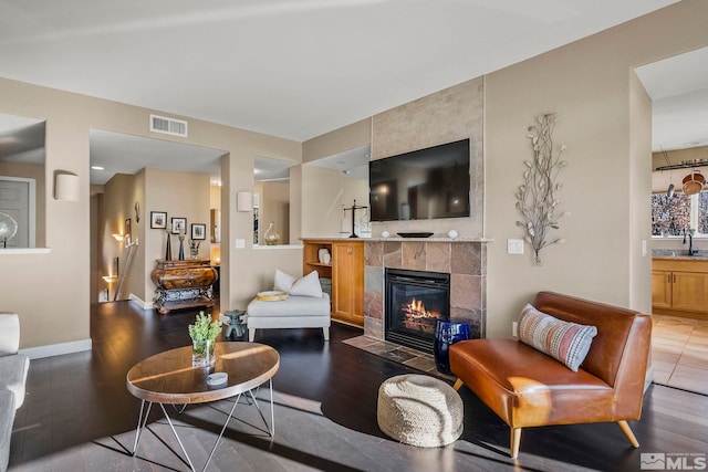 living room with sink, dark hardwood / wood-style flooring, and a fireplace