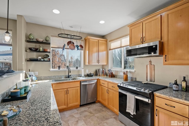 kitchen with sink, decorative light fixtures, light stone counters, and appliances with stainless steel finishes