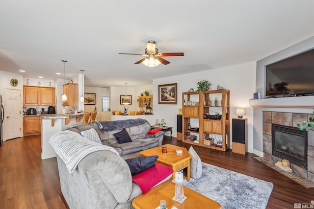 living room with ceiling fan, dark hardwood / wood-style flooring, and a tile fireplace