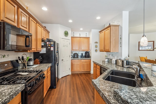 kitchen featuring sink, dark stone countertops, hanging light fixtures, dark hardwood / wood-style floors, and black appliances