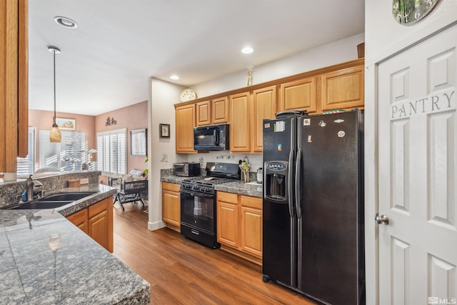 kitchen featuring pendant lighting, black appliances, dark hardwood / wood-style flooring, and sink